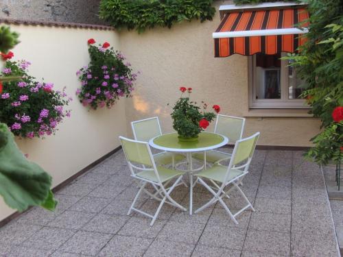 a table and chairs with flowers on a patio at Charmante Chambres d'Hôtes au Cœur des Côtes de Toul, Proche Parc Lorraine & A31 - FR-1-584-189 in Choloy