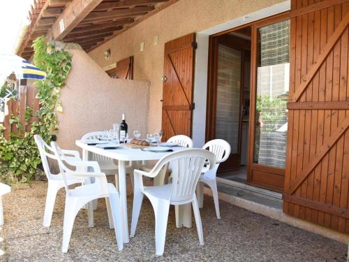 une table blanche et des chaises sur une terrasse dans l'établissement Charmant pavillon 6 couchages à 100m de la plage avec terrasse - Gruissan - FR-1-229-823, à Gruissan