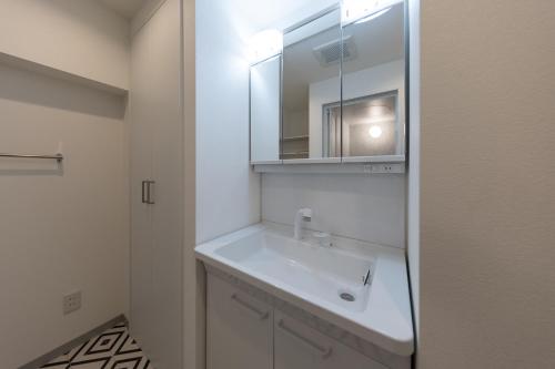 a bathroom with a white sink and a mirror at trive osu kannon 駅チカ 大須商店街スグ 大須観音駅 徒歩30秒の好立地 in Minami-sotoborichō