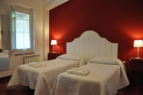 two beds in a room with red walls at Agriturismo Roccadia in Carlentini