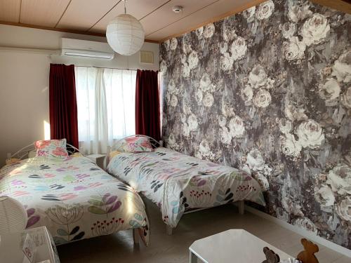 um quarto com 2 camas e um papel de parede floral em B&B HOTTA em Sapporo