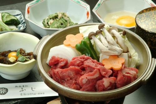 a bowl of food with meat and vegetables on a table at Tabist ホテル富士 in Daisen