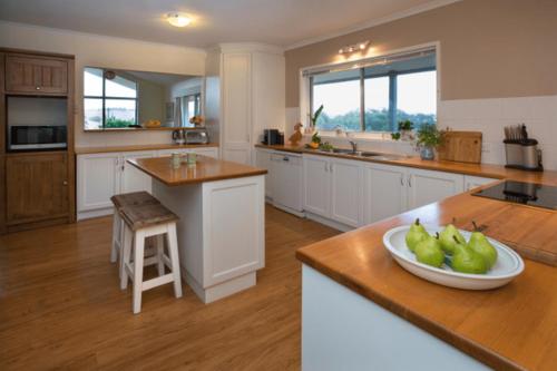 a kitchen with white cabinets and a bowl of pears on the counter at Mhara Downs Country Escape in Foster