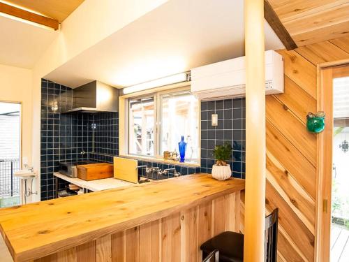 a kitchen with a wooden counter top and black tiles at Trawl Guesthouseトロールゲストハウス in Koshigoe