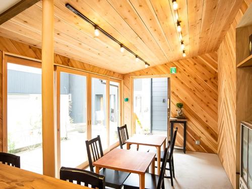comedor con techos de madera, mesas y sillas de madera en Trawl Guesthouseトロールゲストハウス, en Koshigoe