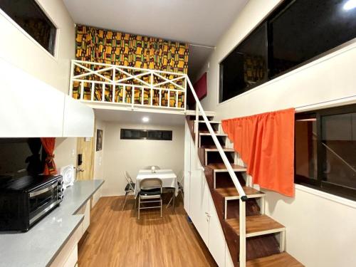 a tiny house with a staircase and a dining room at Tiny house with extended camping area for large groups in Puerto Viejo