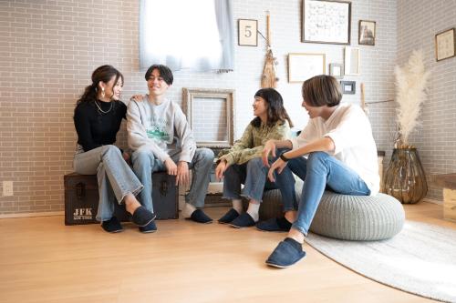 un grupo de personas sentadas en reposapiés en una habitación en trive osu east 駅チカ 大須観音通商店街スグ, en Nagoya