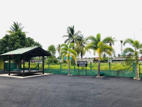 a bus stop with a sign and palm trees at Chalet Sri Damai in Kampong Pengkalan Maras