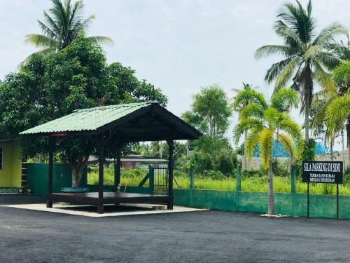 a bus stop with a pavilion in a park with palm trees at Chalet Sri Damai in Kampong Pengkalan Maras