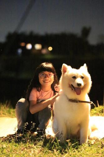 a woman is kneeling next to a white dog at DGD Chiangmai in Mae Rim