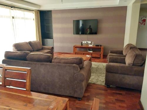 ein Wohnzimmer mit 2 Sofas und einem TV in der Unterkunft Sky view three bedroom in Nairobi