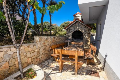 un patio con una mesa de madera y una pared de piedra en Apartments Ned, en Mandre
