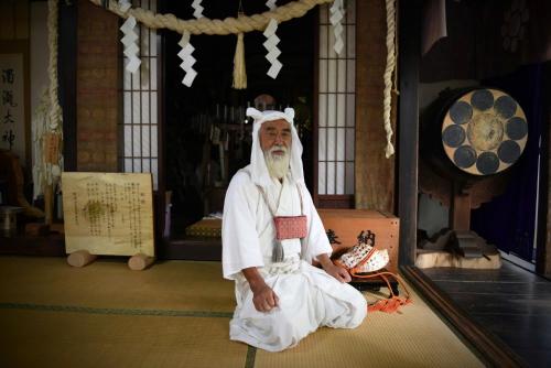 Un uomo seduto sul pavimento in una stanza di 大聖坊 Daishobo a Tsuruoka