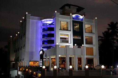a large white building with a clock in front of it at Athirappilly Residency Chalakudy in Kizhake Chālakudi