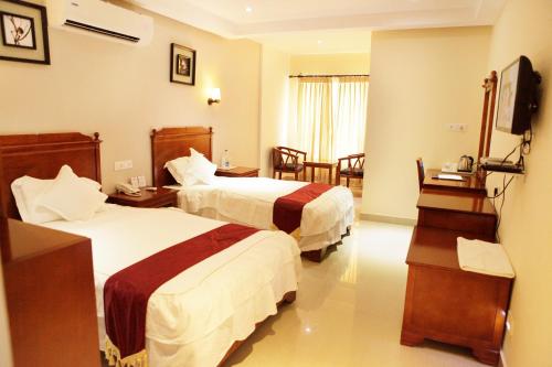 a hotel room with two beds and a television at Athirappilly Residency Chalakudy in Kizhake Chālakudi