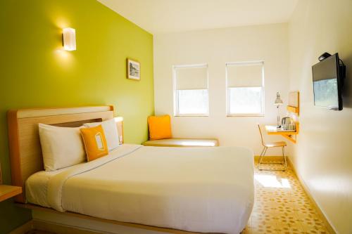 a bedroom with a large white bed with orange pillows at Bloom Hotel - Calangute in Calangute