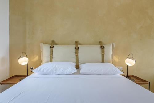 a bed with two white pillows and two lamps at Agrielia Studios Katigiorgis, Agios Georgios in Agios Georgios