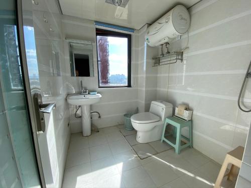 a white bathroom with a toilet and a sink at 合家欢 in Kunming