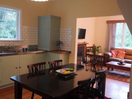 a kitchen and living room with a table and chairs at Tinui Food Forest Cottage in Whareama