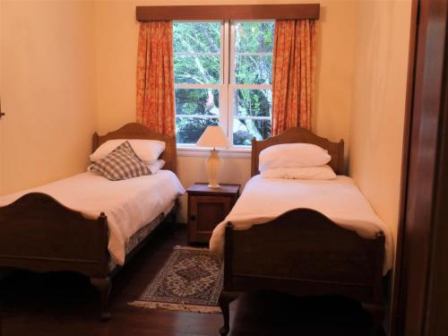 2 camas en una habitación con ventana en Tinui Food Forest Cottage en Whareama