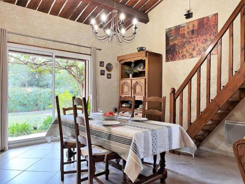 une salle à manger avec une table et un lustre dans l'établissement Maison cosy avec mezzanine, jardin et terrasse à 600m de la plage de Saint-Clair, 6 couchages - FR-1-251-46, au Lavandou