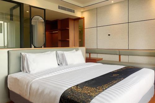 a bedroom with a large bed with white sheets and pillows at Grand Miami Hotel in Malang