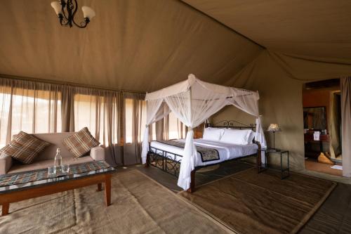 - une chambre avec un lit à baldaquin dans une tente dans l'établissement Serengeti Woodlands Camp, à Serengeti