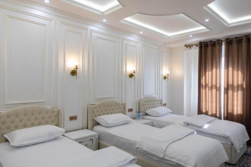 3 posti letto in una stanza con pareti bianche di Ardani hotel,Samarqand a Khodzha-Akhrar