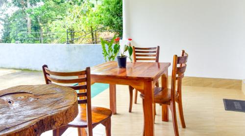 a wooden table and chairs with a plant on a patio at Ella Nimal Nest Inn in Ella