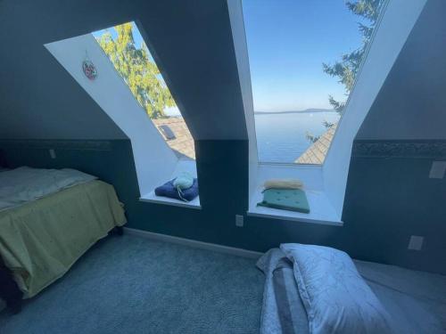 1 dormitorio con 2 ventanas, 1 cama y el océano en Vancouver Castle Waterfront with hot tub beach downtown, en Chemainus