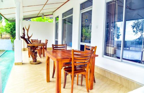 a wooden table and chairs on the porch of a house at Ella Nimal Nest Inn in Ella