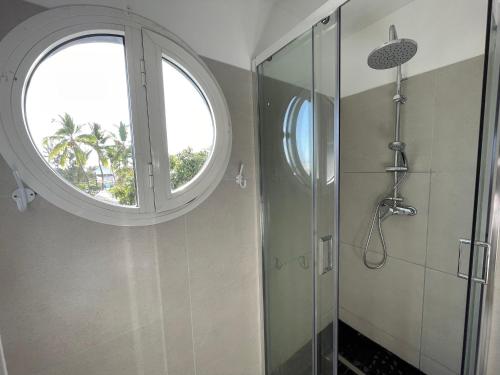 a bathroom with a round window and a shower at La Croisette appartement vue mer à 1mn de la plage + parking in Filaos