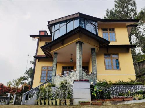 a yellow house with a balcony on top of it at Villa Mawar Bumi Citeko in Bogor