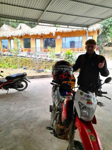a man is standing next to a motorcycle at Thao Ly Homestay Mai Chau in Hòa Bình