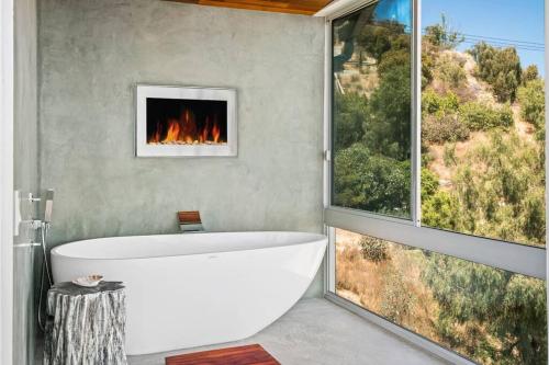 a bathroom with a bath tub and a fireplace at Malibu Glass House: Architectural w 180deg Views in Malibu