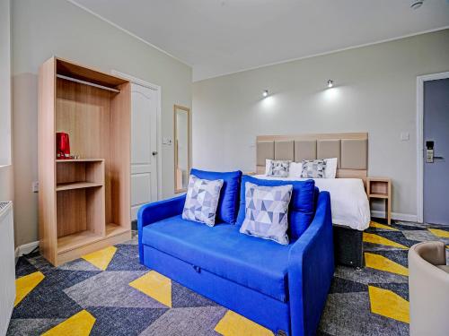 1 dormitorio con sofá azul y cama en Weaste Hotel, West Manchester en Mánchester