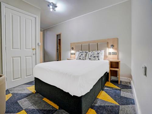 a bedroom with a large white bed and a yellow floor at Weaste Hotel, West Manchester Hotel in Manchester