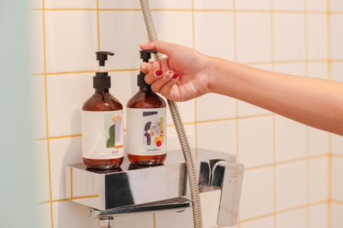 a person is holding two bottles of wine on a shelf at Kotta Hotel Semarang in Semarang