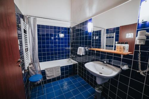 a blue tiled bathroom with a sink and a tub at Hotel Centrum in Hranice