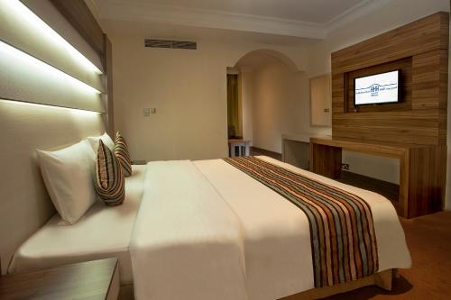 a bedroom with a white bed and a television at HAFFA HOUSE HOTEL in Muscat