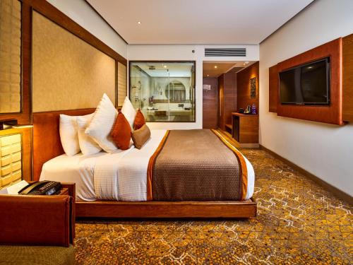 ein Hotelzimmer mit einem Bett und einem Flachbild-TV in der Unterkunft Sayaji Indore in Indore