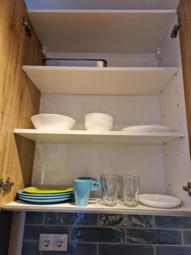a shelf with plates and bowls and glasses on it at Apartment next to Mall Plovdiv in Plovdiv
