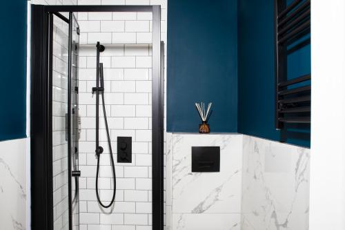 a bathroom with a shower with blue walls and white tiles at Bob W Hyde Park in London