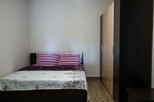 1 dormitorio con 1 cama con almohadas rosas y moradas en Διαμέρισμα κοντά στο μουσείο τρένων, en Drama