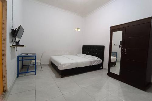 a bedroom with a bed and a tv and a mirror at OYO 92176 Sandira Syariah in Dumai