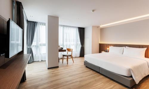 a hotel room with a large bed and a desk at Pure Eleven Hotel Bangkok in Makkasan