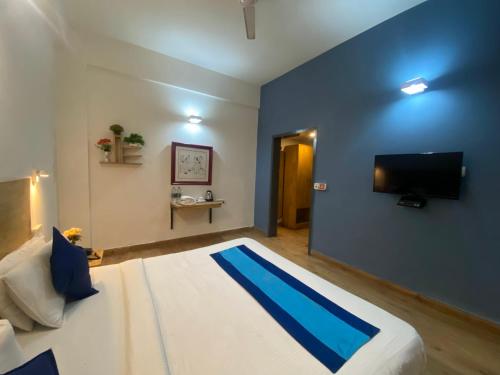 a bedroom with a large bed and a flat screen tv at Divine Inn Couple Friendly Hotel near Sector 51 Metro Station in Noida