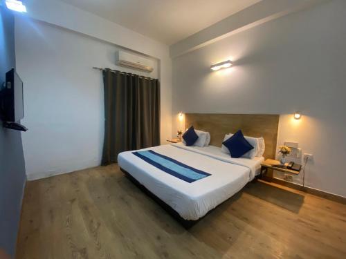 a bedroom with a large white bed with blue pillows at Divine Inn Couple Friendly Hotel near Sector 51 Metro Station in Noida