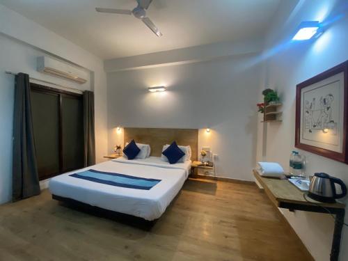 1 dormitorio con 1 cama blanca grande con almohadas azules en Divine Inn Couple Friendly Hotel near Sector 51 Metro Station, en Noida