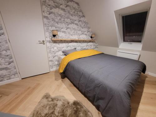 een slaapkamer met een bed met een stenen muur bij Les apparts de Léon in Landerneau